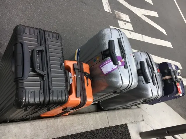 Image of an airport transfer service loading large suitcases and golf bags into an Alphard